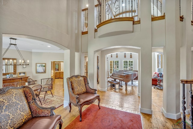 entrance foyer featuring baseboards, arched walkways, hardwood / wood-style flooring, ornamental molding, and a high ceiling