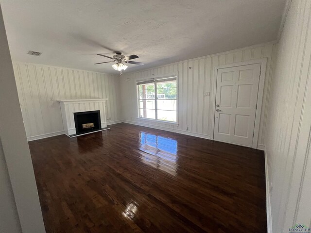 unfurnished living room featuring a fireplace with raised hearth, ceiling fan, visible vents, ornamental molding, and dark wood-style floors