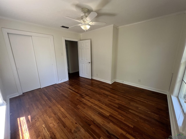 unfurnished bedroom featuring dark wood-style floors, visible vents, a ceiling fan, a closet, and ornamental molding