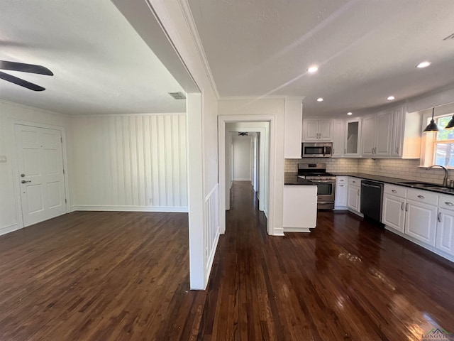 kitchen featuring stainless steel appliances, a sink, dark countertops, and crown molding