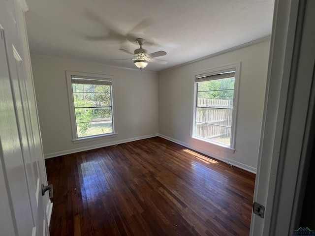 empty room with a healthy amount of sunlight, crown molding, baseboards, and dark wood-style flooring