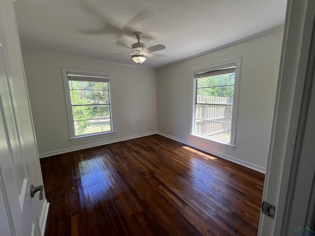 empty room featuring a wealth of natural light, dark wood-style floors, and baseboards
