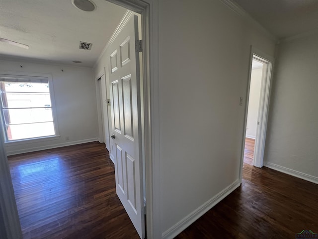 corridor with baseboards, visible vents, dark wood-type flooring, and ornamental molding
