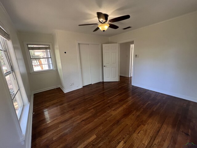 unfurnished bedroom featuring baseboards, visible vents, a closet, dark wood-type flooring, and ornamental molding
