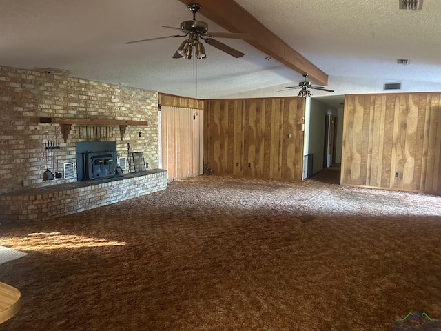 unfurnished living room featuring wooden walls, beamed ceiling, a textured ceiling, and ceiling fan