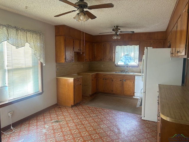 kitchen with a textured ceiling, white appliances, ceiling fan, and sink