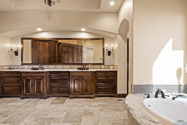 bathroom featuring backsplash, vanity, and a bath