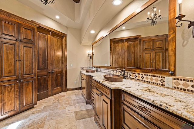 bathroom with a notable chandelier, vanity, and backsplash