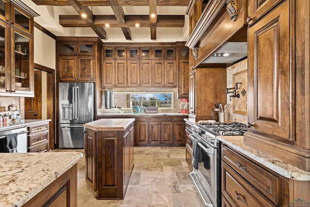 kitchen with beam ceiling, light stone counters, high quality appliances, a kitchen island, and custom exhaust hood