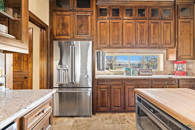 kitchen with butcher block countertops, built in microwave, high quality fridge, and tasteful backsplash