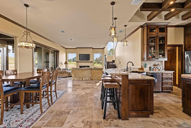 kitchen featuring beam ceiling, light stone countertops, sink, stainless steel appliances, and pendant lighting