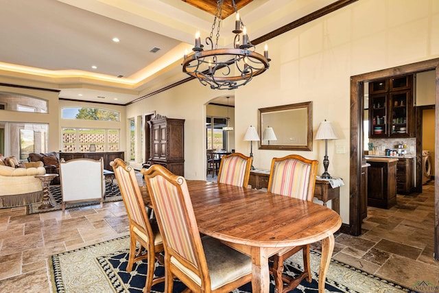 dining room with a chandelier, a towering ceiling, a raised ceiling, and plenty of natural light