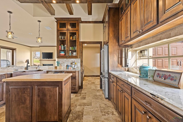 kitchen with beam ceiling, sink, wood counters, high quality fridge, and a kitchen island