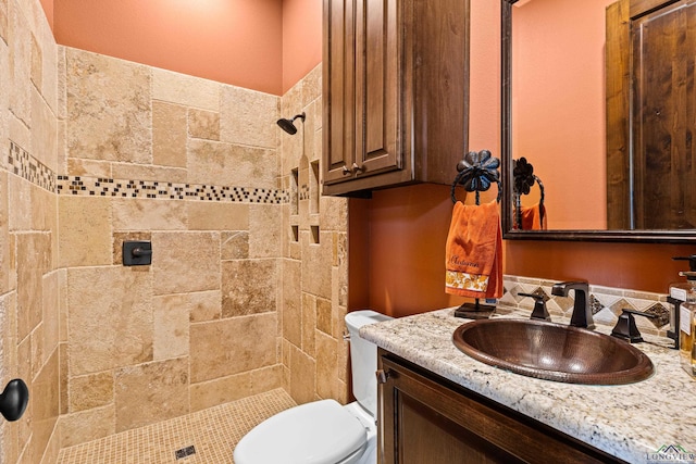 bathroom featuring tiled shower, vanity, and toilet