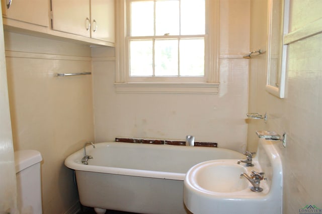 bathroom featuring a tub to relax in, toilet, and sink