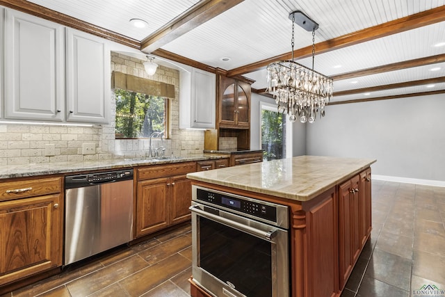 kitchen with backsplash, stainless steel appliances, sink, a notable chandelier, and a kitchen island