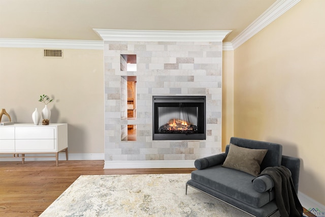 sitting room with a tile fireplace, crown molding, and light hardwood / wood-style floors