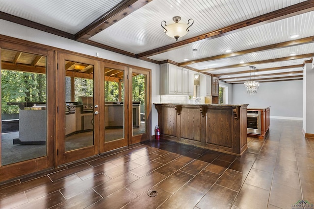 kitchen featuring kitchen peninsula, a kitchen bar, a notable chandelier, wine cooler, and hanging light fixtures