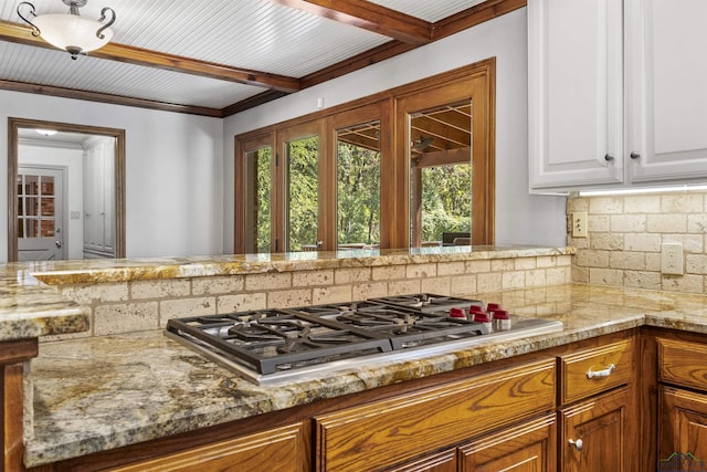 kitchen with tasteful backsplash, light stone countertops, white cabinets, and stainless steel gas stovetop