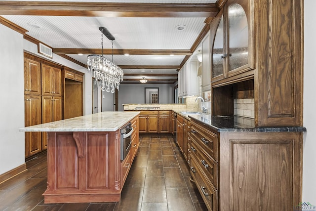 kitchen with stainless steel oven, sink, a notable chandelier, backsplash, and kitchen peninsula