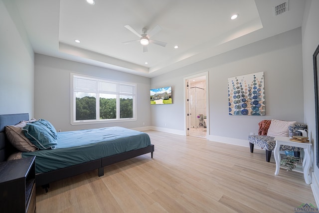 bedroom featuring ceiling fan, a raised ceiling, and light wood-type flooring