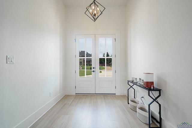 doorway featuring french doors, light hardwood / wood-style floors, and a notable chandelier