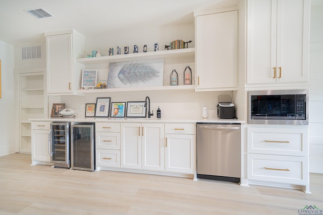 bar featuring built in microwave, dishwasher, white cabinets, and light hardwood / wood-style flooring