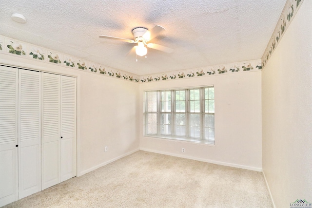 unfurnished bedroom with ceiling fan, a closet, light colored carpet, and a textured ceiling