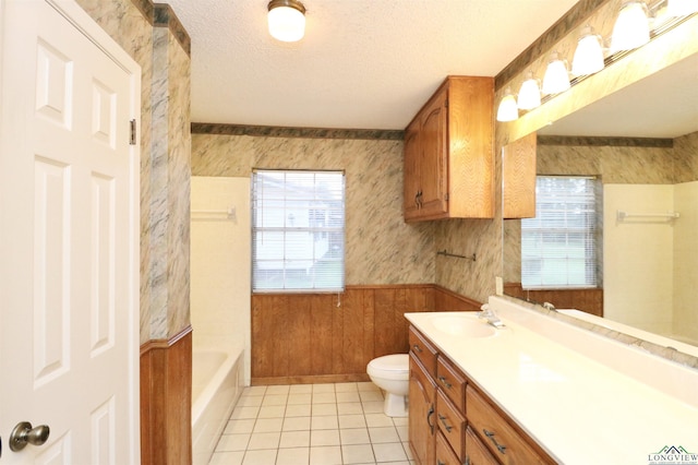 bathroom with tile patterned floors, a textured ceiling, vanity, toilet, and wood walls