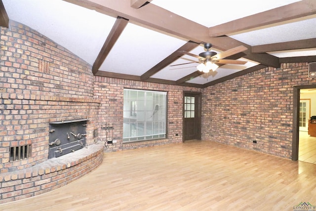 unfurnished living room with vaulted ceiling with beams, ceiling fan, a fireplace, and hardwood / wood-style flooring