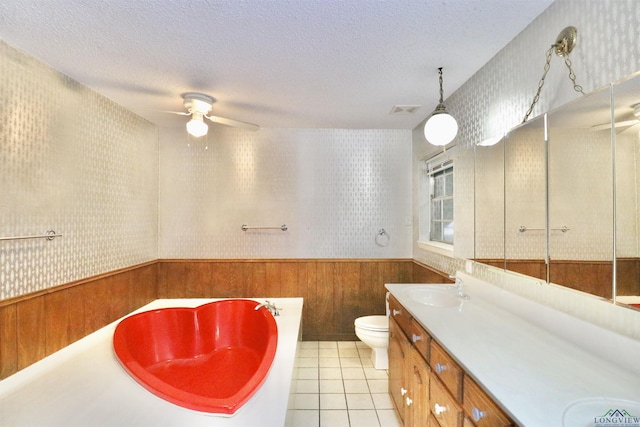 bathroom featuring a textured ceiling, wood walls, toilet, and a bath