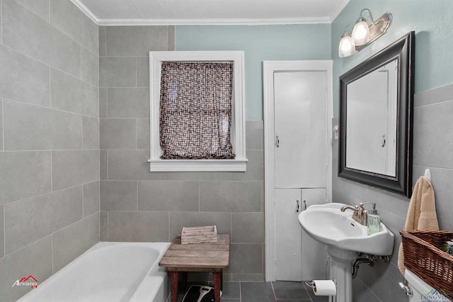 bathroom featuring tile patterned floors, a bathing tub, crown molding, and tile walls