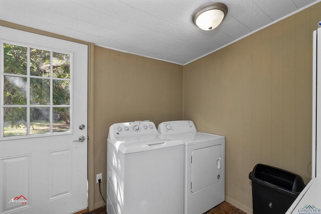 clothes washing area featuring wooden walls and washer and dryer