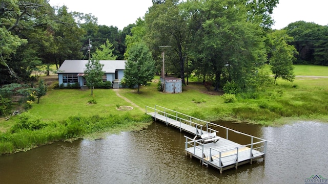 view of dock with a lawn and a water view