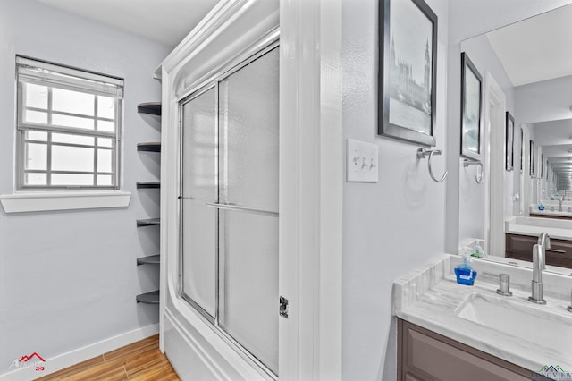 3718 Ben Hogan Dr, Longview, TX 75605 - full bath featuring vanity, wood finished floors, baseboards, and shower / bath combination with glass door