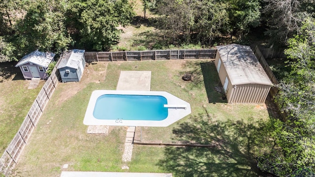 view of swimming pool with a yard, a shed, and a diving board