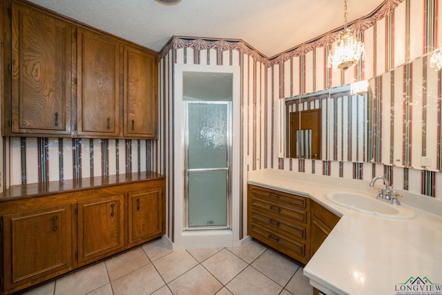 bathroom with tile patterned floors, walk in shower, vanity, a textured ceiling, and a notable chandelier