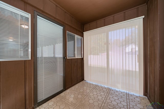 interior space featuring light tile patterned flooring and wood walls