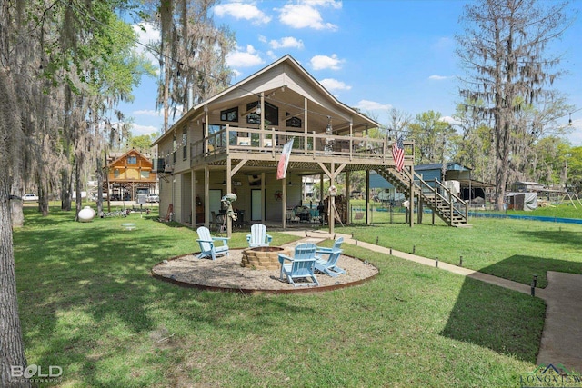 back of property featuring a lawn, a wooden deck, a patio, and an outdoor fire pit