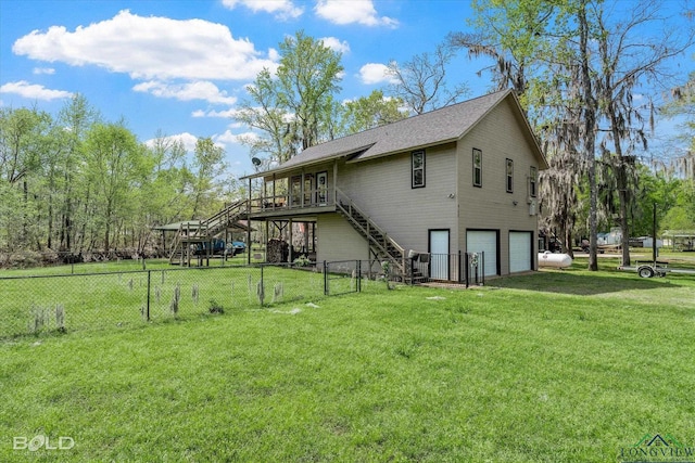 rear view of property featuring a yard, a garage, and a deck