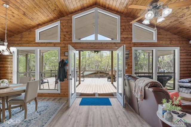 living room featuring ceiling fan with notable chandelier, log walls, wooden ceiling, light hardwood / wood-style floors, and plenty of natural light