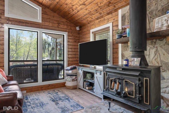 living room with plenty of natural light, a wood stove, rustic walls, and lofted ceiling