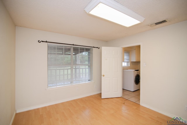 empty room with hardwood / wood-style floors, a textured ceiling, and washer / clothes dryer