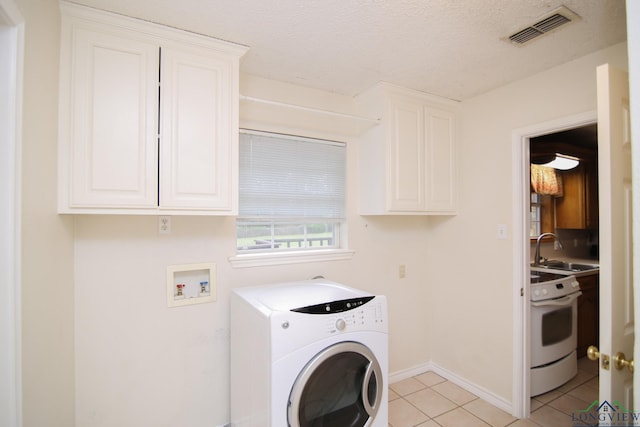 laundry room featuring cabinets, sink, a textured ceiling, light tile patterned flooring, and washer / dryer