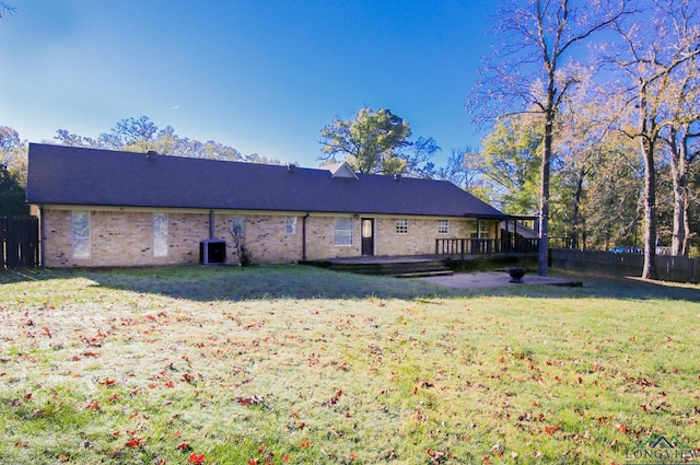 rear view of property featuring a lawn, central air condition unit, and a deck