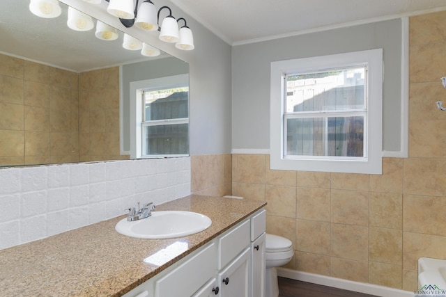 bathroom with vanity, toilet, crown molding, and tile walls