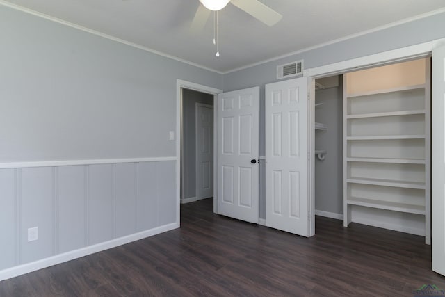 unfurnished bedroom with ceiling fan, dark hardwood / wood-style flooring, crown molding, and a closet