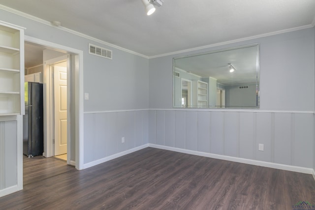 spare room featuring crown molding, dark wood-type flooring, and track lighting