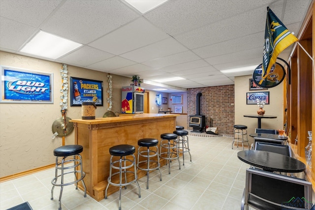 bar featuring tile patterned floors, a wood stove, and a drop ceiling