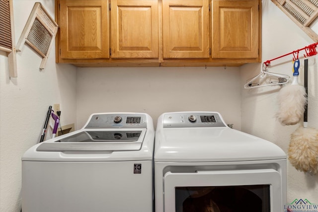 laundry room with washing machine and clothes dryer and cabinets